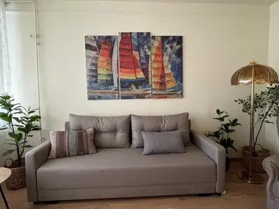 a couch in a living room with two paintings on the wall at R&R Apartmant Konjarnik in Belgrade