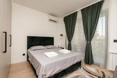 a bedroom with a large bed with green curtains at BW Simfonija 1 in Belgrade