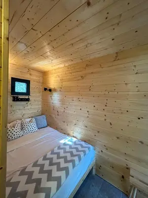 a room with a bed in a wooden room at Cabin 16 in Čolakovica Potok