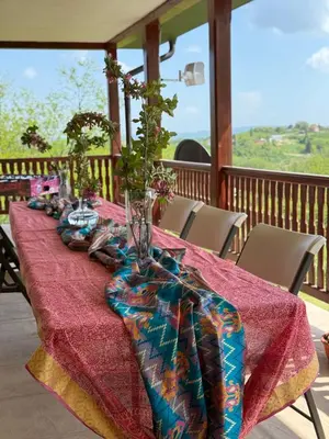 a table with a red table cloth and a vase on it at Zen Cherry House- Vikendica na dan sa bazenom1,5ha izmedju Avale i Kosmaja in Drobnjaci