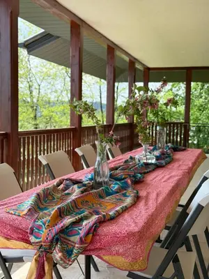 a table with vases and flowers on a porch at Zen Cherry House- Vikendica na dan sa bazenom1,5ha izmedju Avale i Kosmaja in Drobnjaci