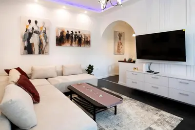 a living room with a white couch and a flat screen tv at The Belfort Townhomes - Lux Salon in Belgrade