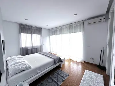 a bedroom with a bed and two large windows at Triplex with garden and parking in Belgrade
