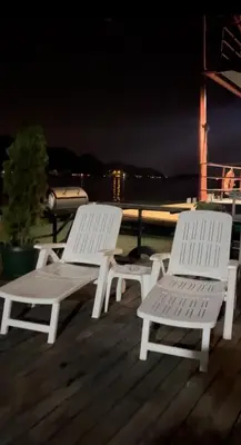 two white benches sitting on a deck at night at Splav na Savi KALIVARIJA in Belgrade