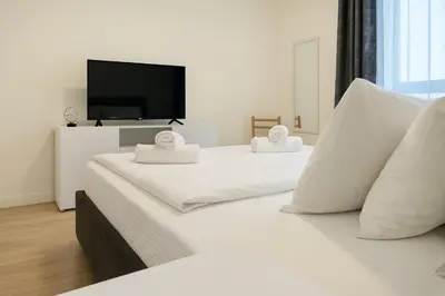 a bedroom with two white beds with a flat screen tv at Queen's Park Residence Apartments in Belgrade