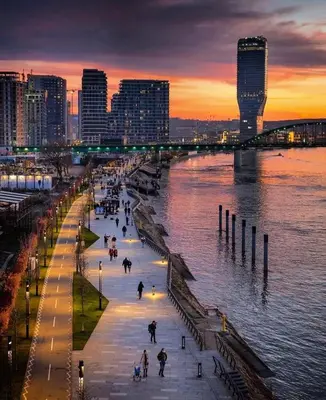 a city with people walking on a sidewalk near the water at Queen's Park Residence Apartments in Belgrade