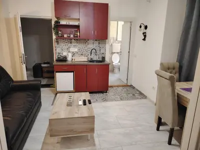 a kitchen with red cabinets and a table in a living room at Nefertiti Apartment in Belgrade