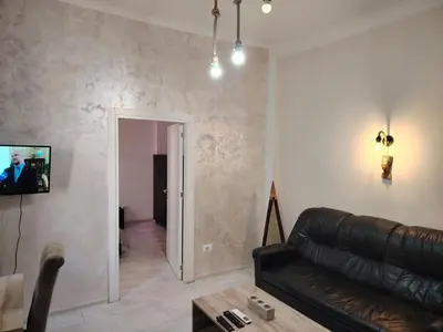 a living room with a couch and a tv on a wall at Nefertiti Apartment in Belgrade