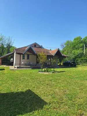 a house with a grass yard in front of it at Nasa kuca in Gročanska Ada