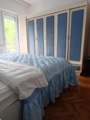 a bedroom with a bed with blue sheets and windows at SREMICA - Guest House in Pećinci