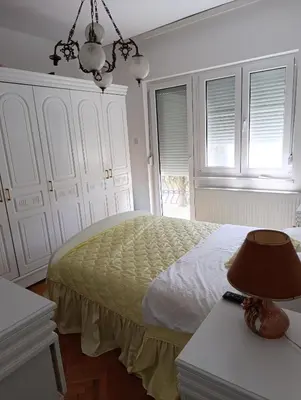 a bedroom with a bed and a lamp on a table at SREMICA - Guest House in Pećinci
