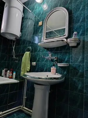 a green tiled bathroom with a sink and a mirror at SREMICA - Guest House in Pećinci