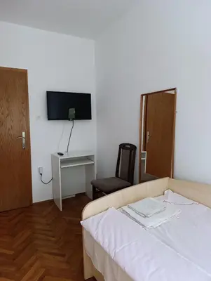 a bedroom with a bed and a desk and a tv at SREMICA - Guest House in Pećinci