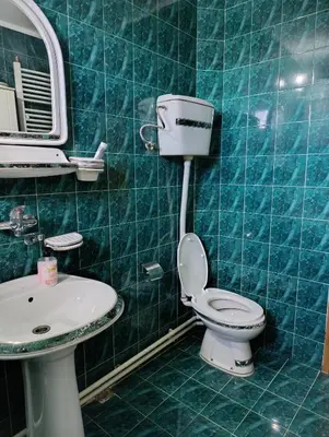 a blue tiled bathroom with a toilet and a sink at SREMICA - Guest House in Pećinci