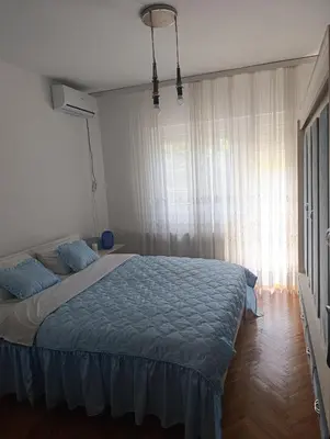 a bedroom with a bed with blue pillows and a window at SREMICA - Guest House in Pećinci