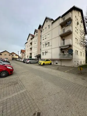 a building with cars parked in a parking lot at DP Lux apartman Obrenovac,sa parkingom in Obrenovac