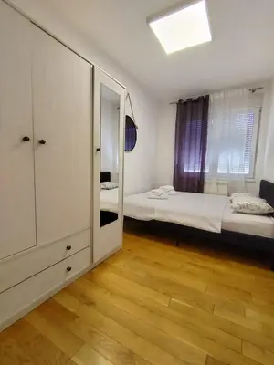 a small room with a bed and a mirror at Benvenuti HONEY in Zemun