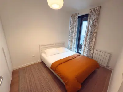 a bedroom with an orange bed and a window at K-District Apartment Charlie in Belgrade