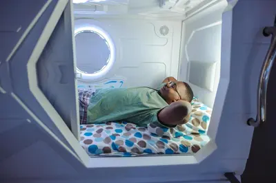 a man laying on a bed in a hospital room at Belgrade Beocean Capsule Hostel in Belgrade