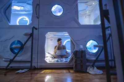 a woman sitting on a bed in an aquarium at Belgrade Beocean Capsule Hostel in Belgrade