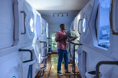 a man standing in a hospital room with beds at Belgrade Beocean Capsule Hostel in Belgrade
