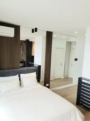 a bedroom with a large white bed and a kitchen at Beograd na vodi - Belgrade Waterfront Luna Apartment in Belgrade