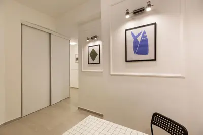 a hallway with a chair and paintings on the wall at High Note Suites in Belgrade