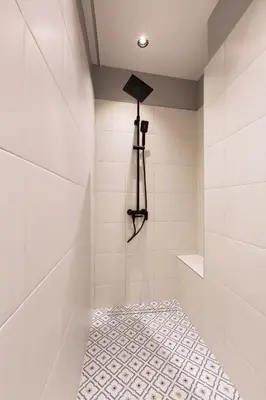 a white tiled bathroom with a shower with a spotlight at High Note Suites in Belgrade