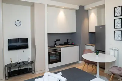 a kitchen with white cabinets and a table in a room at Talija BW in Belgrade