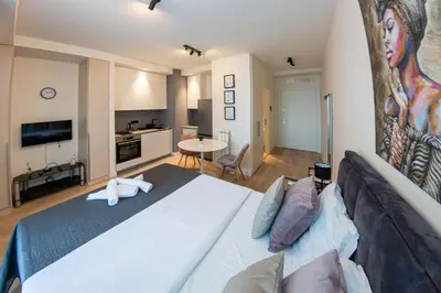a bedroom with a large white bed and a kitchen at Talija BW in Belgrade