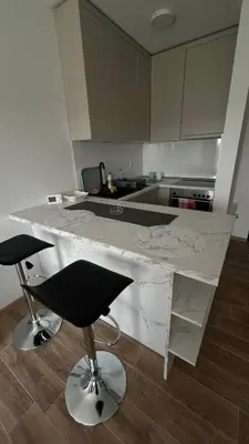 a kitchen with a white counter and two bar stools at Stan na dan Indjija in Inđija
