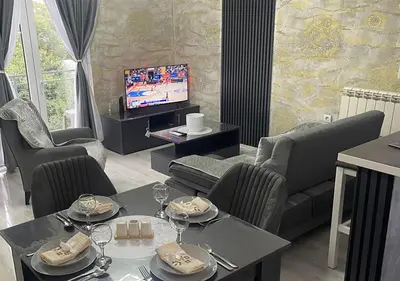 a living room with a table and chairs and a television at Apartman Manda 2 in Belgrade