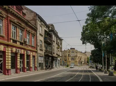 an empty city street with buildings and a car on the road at Pablo MovieSTAR in Belgrade