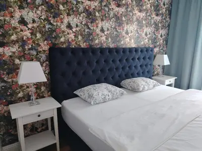 a bed with a blue headboard and two tables with lamps at Benvenuti MOON in Belgrade