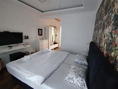 a bedroom with a white bed and a television at Benvenuti MOON in Belgrade