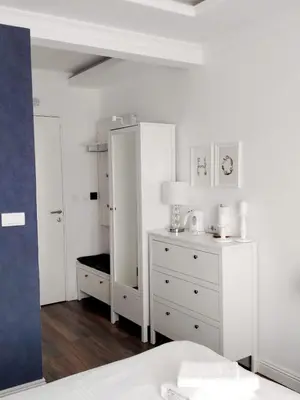 a white bedroom with a bed and a dresser at Benvenuti STAR in Belgrade