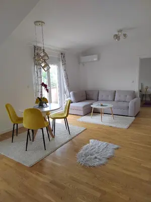 a living room with a couch and a table and chairs at Lux Apartman Banjica in Bukorovac