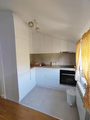 a kitchen with white cabinets and a stove top oven at Lux Apartman Banjica in Bukorovac