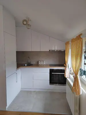 a kitchen with white cabinets and a sink at Lux Apartman Banjica in Bukorovac