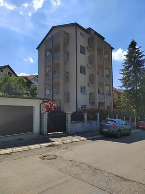 a building with a car parked in front of it at Lux Apartman Banjica in Bukorovac