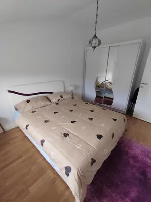 a bed in a bedroom with a purple rug at Lux Apartman Banjica in Bukorovac