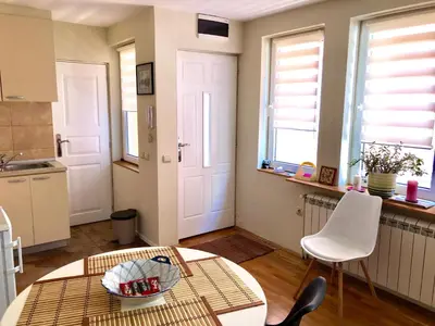 a kitchen with a table and chairs and windows at ZeMoon Apartment in Belgrade