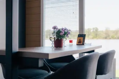 a table with chairs and a vase of flowers on it at Splav na Savi - House on the river in Ostrvo Sprud