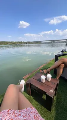 a woman with her feet on a table next to the water at Splav na Savi - House on the river in Ostrvo Sprud