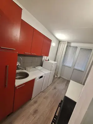 a small kitchen with red cabinets and a sink at Stan na dan Banovo brdo in Belgrade