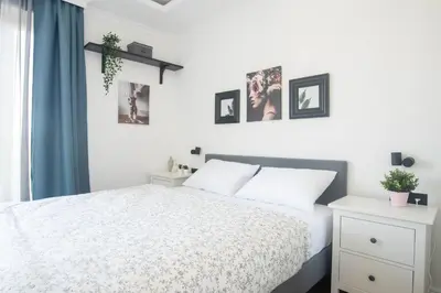 a bedroom with a white bed and some pictures on the wall at Benvenuti FAMILY in Belgrade