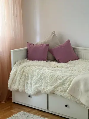 a bed with purple and white pillows on it at Cozy Work-Friendly flat with Backyard near forest in Belgrade