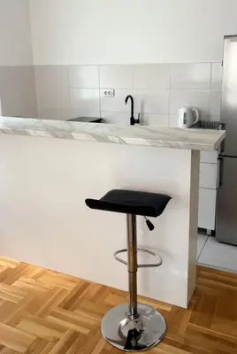 a bar stool in a kitchen with a counter at Cozy Work-Friendly flat with Backyard near forest in Belgrade