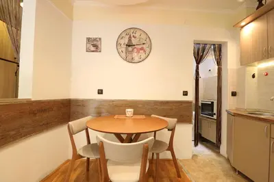 a kitchen with a table and a clock on the wall at Studio Apartman Vladar in Belgrade