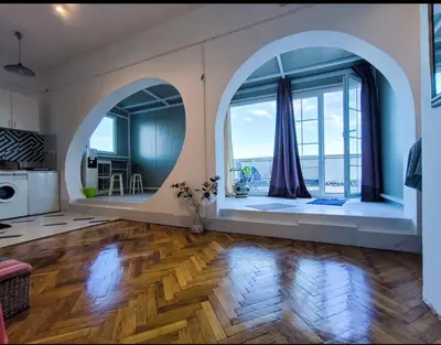 a large living room with an arched window and wooden floors at on top of the city in Belgrade